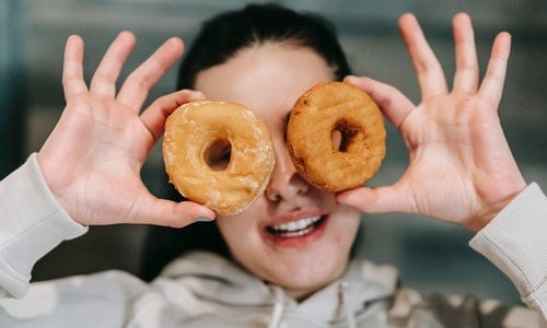 woman holds up two donuts